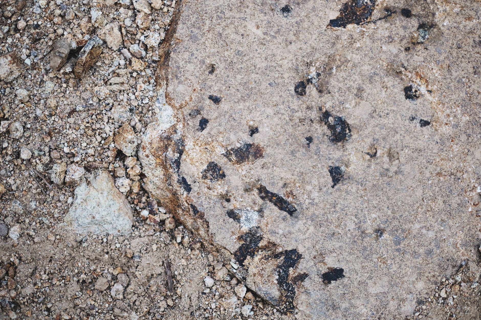 rock pick hammer resting on desert ground near quartz and basalt rocks