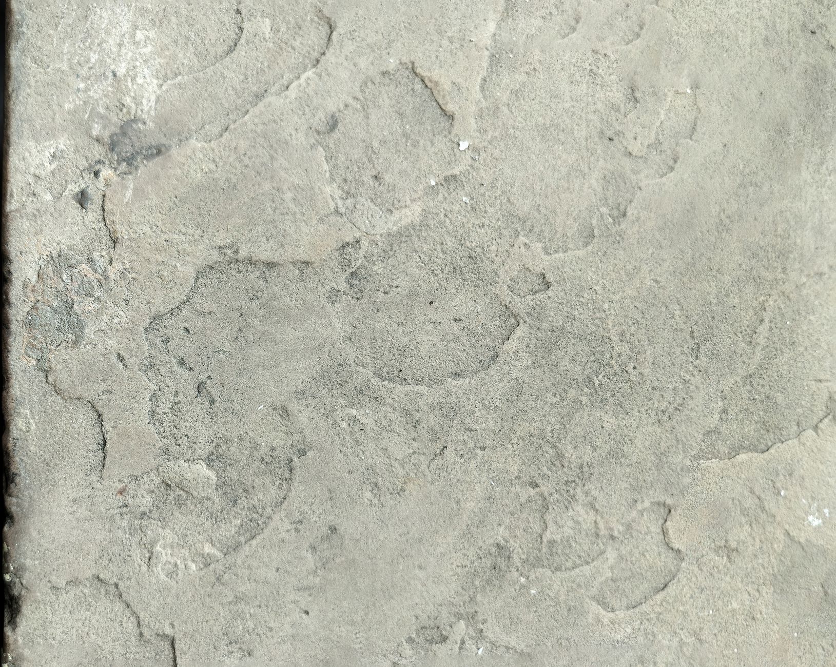 a hand rubbing a brassy pyrite chunk across a white unglazed porcelain tile leaving a dark streak