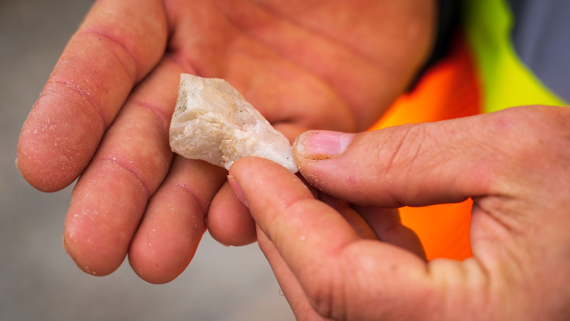 A rockhound holds a translucent quartz crystal up to sunlight in a desert landscape