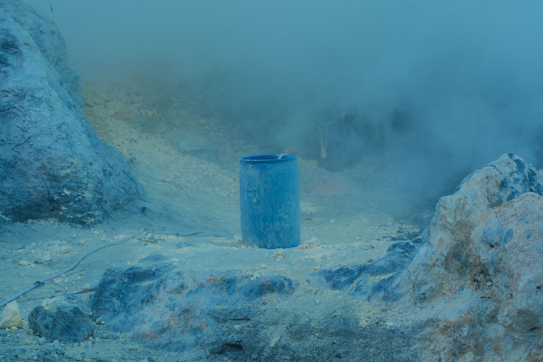 an open rock tumbler barrel showing rocks covered in gray grinding slurry