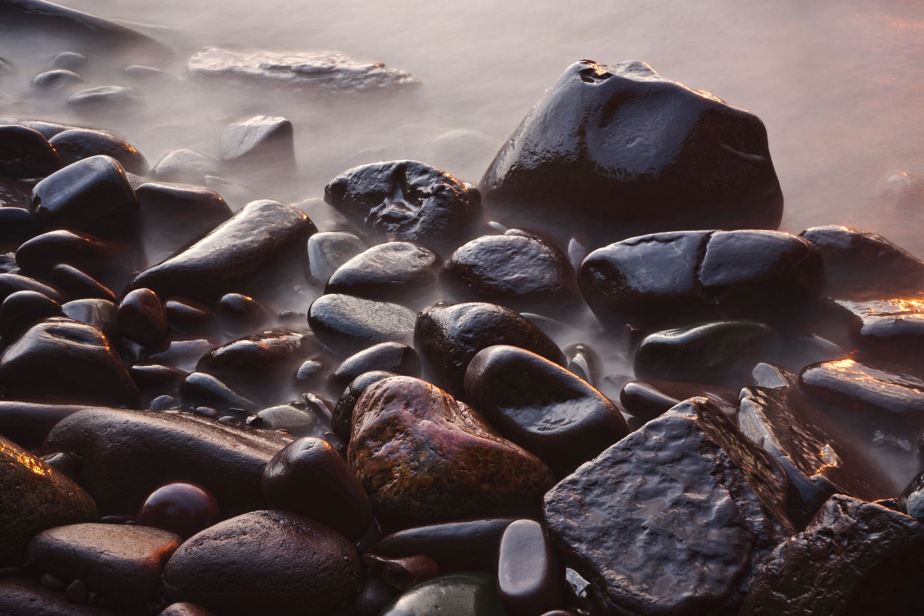 a bucket of Lake Superior agates being rinsed with water on a shoreline