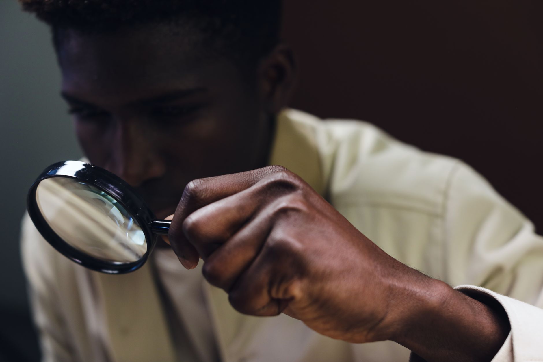 person inspecting a small green emerald crystal using a magnifying loupe