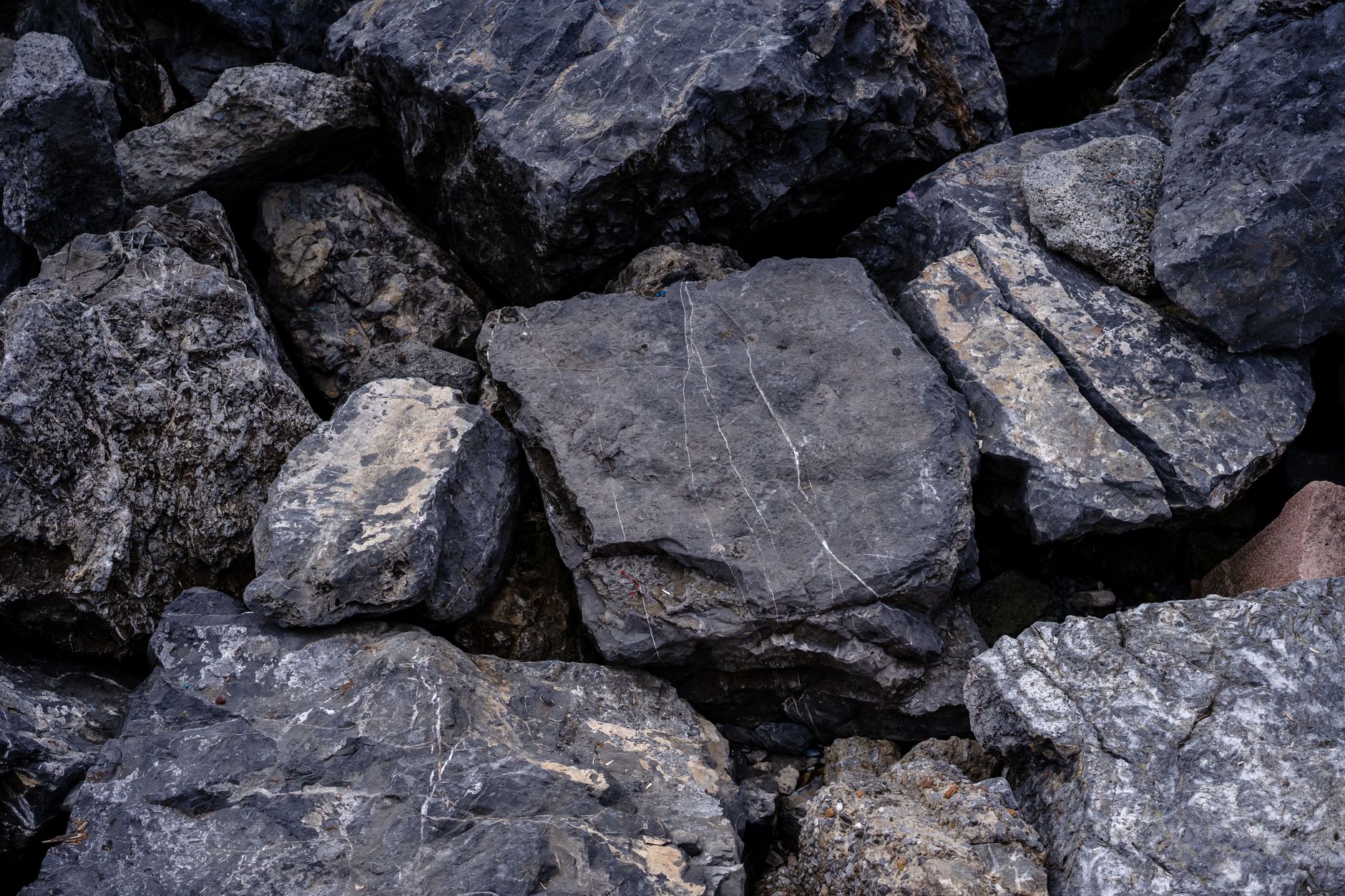 rock hammer, safety glasses, and gloves next to a pile of rough minerals