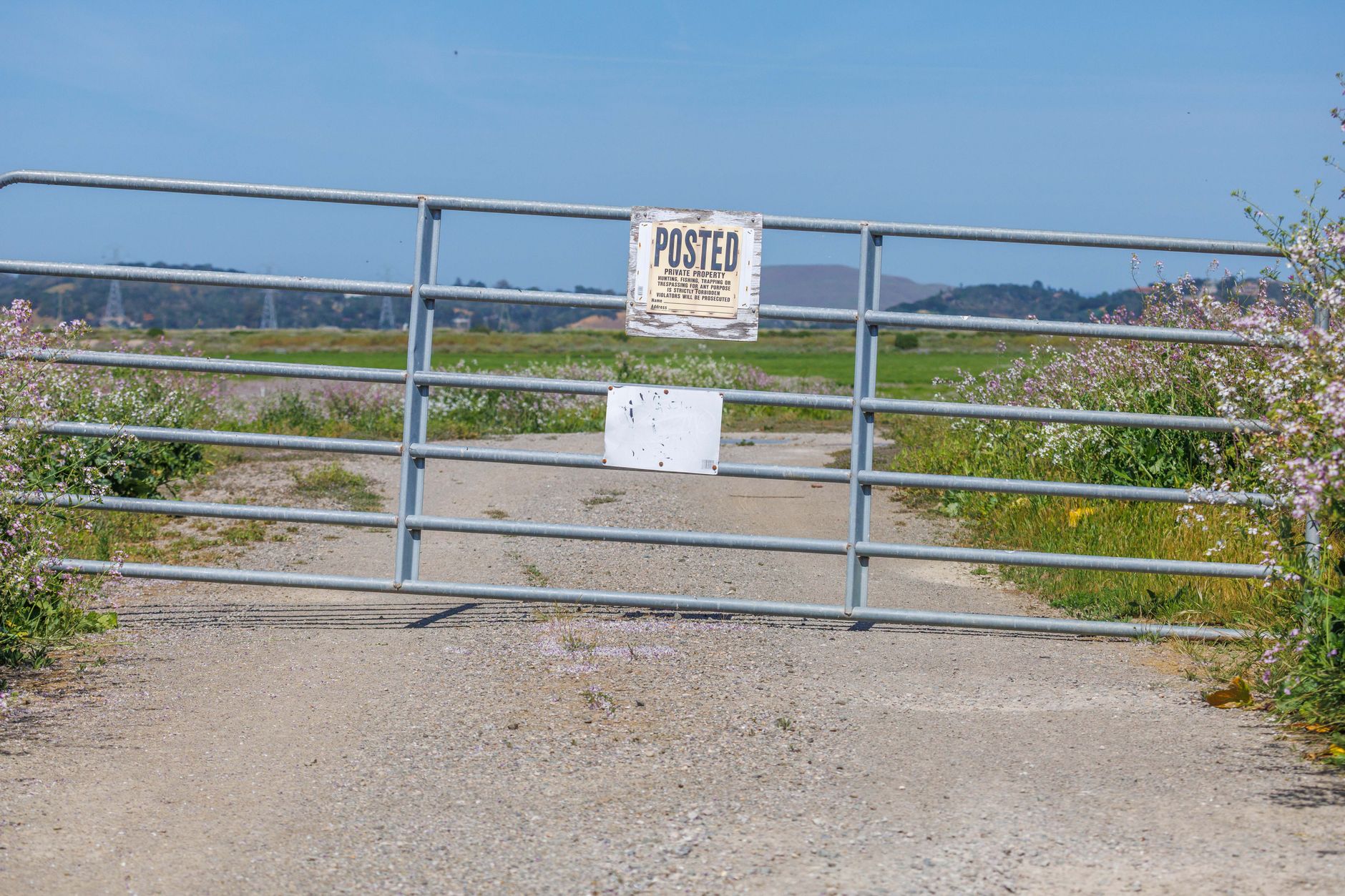 a metal ranch gate beside a gravel road in the Texas Hill Country
